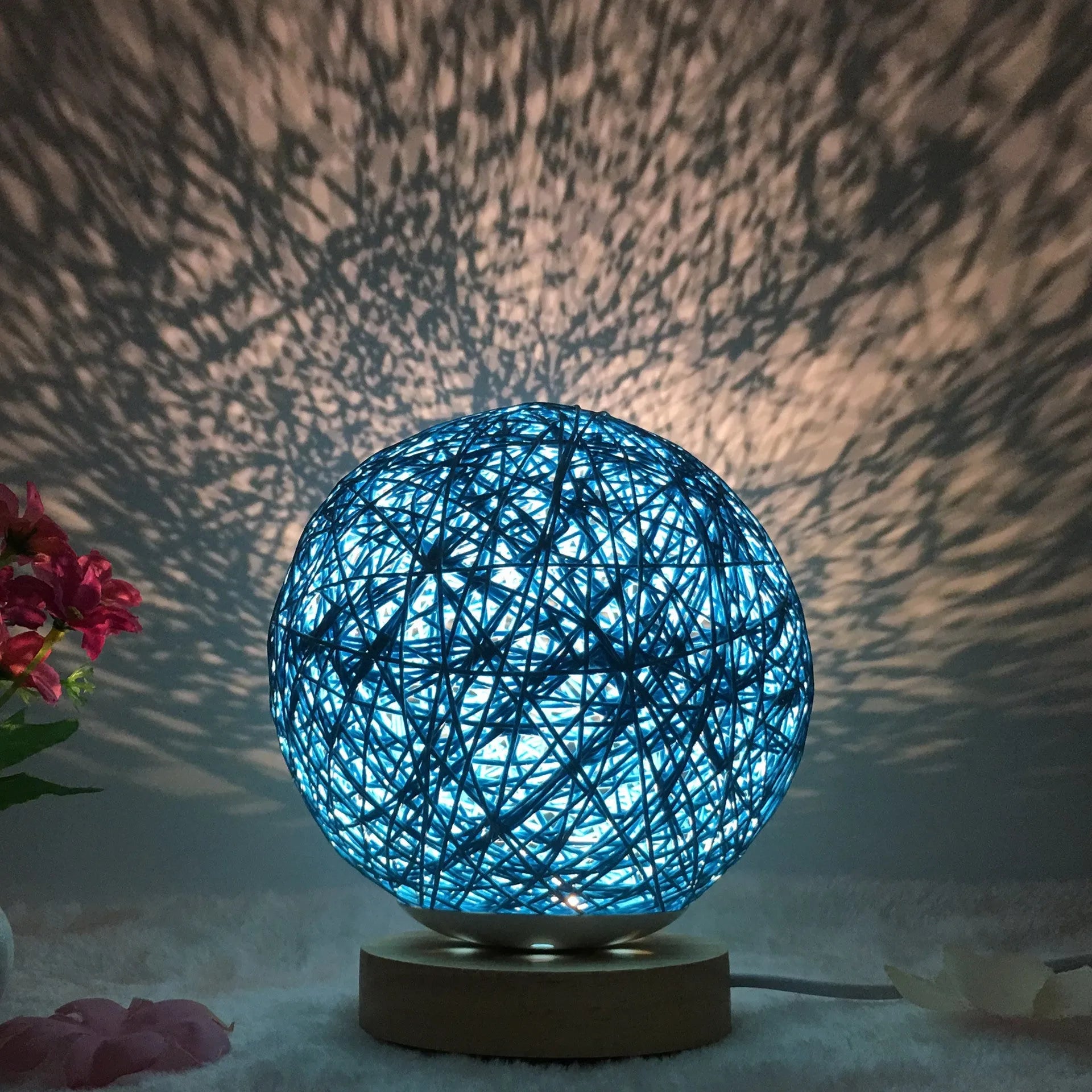 Rattan ball table lamp with woven shade and warm LED lighting on wooden surface
