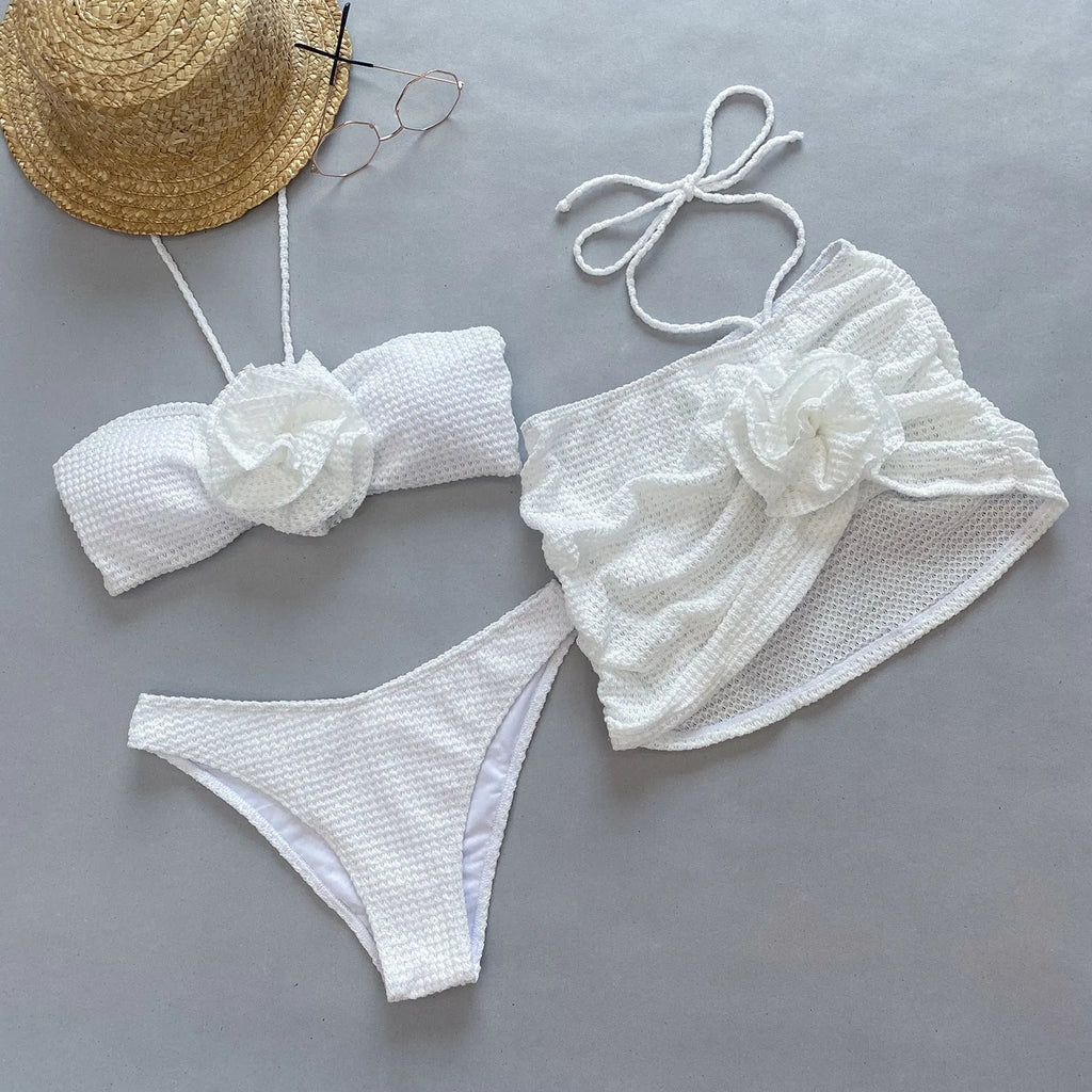 Women's white 3D flower split three-piece bikini swimsuit set with bra, briefs, and skirt on a mannequin.
