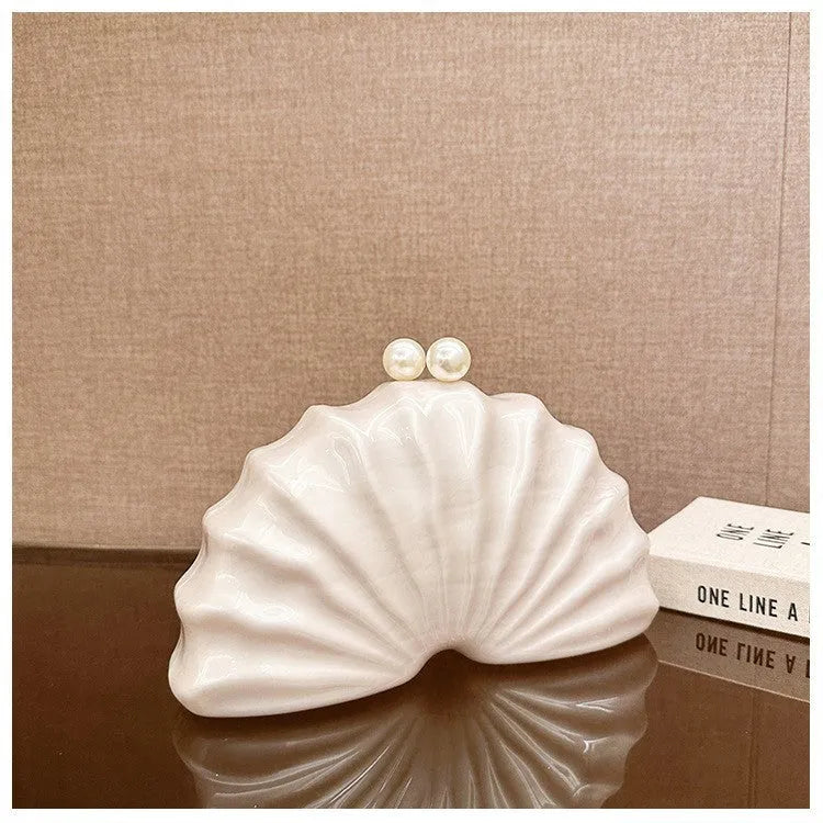 Acrylic shell-shaped clutch bag in champagne with silver chain on white background
