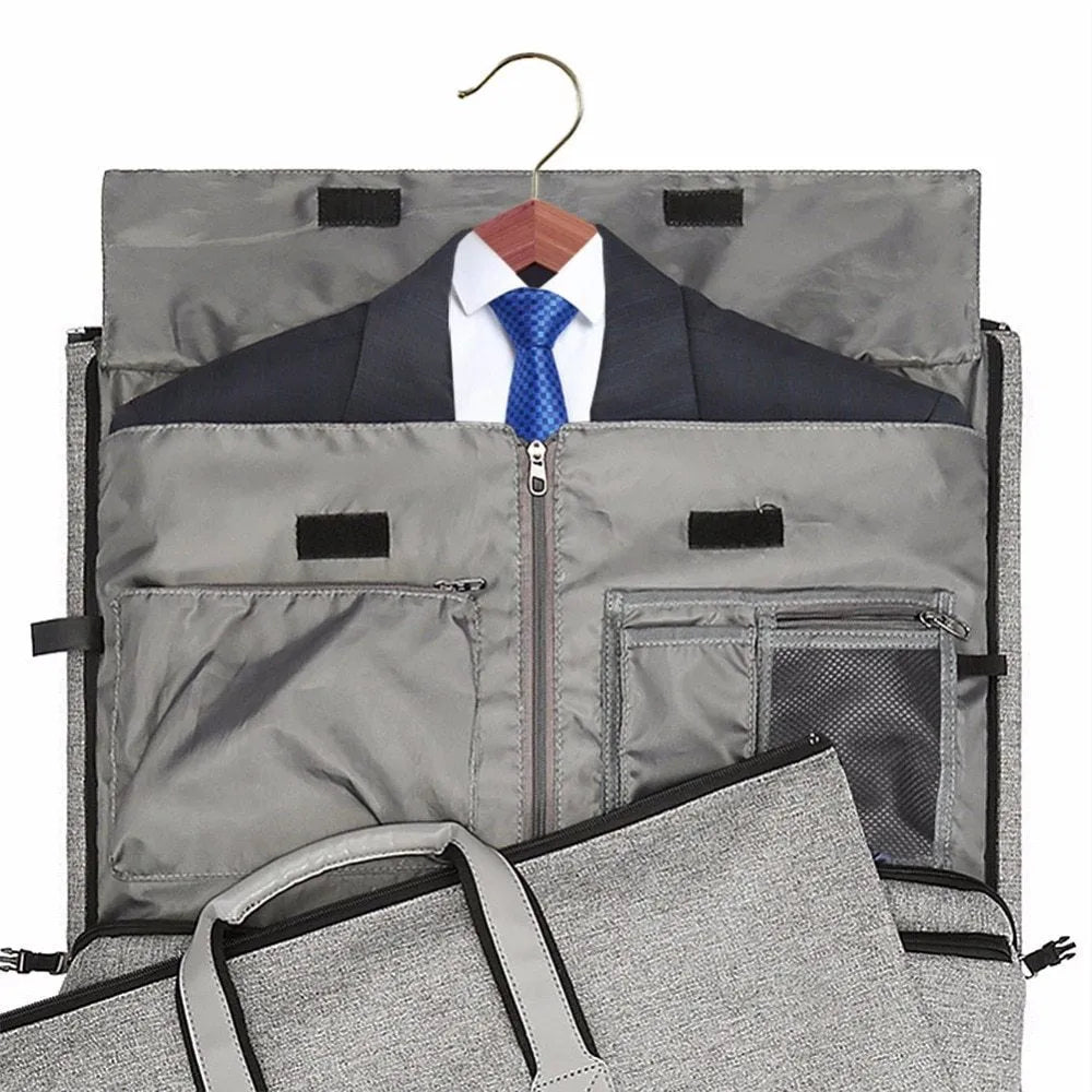 Travel garment bag in black and gray with adjustable shoulder strap, hanging suit carrier, and multiple pockets on a neutral background