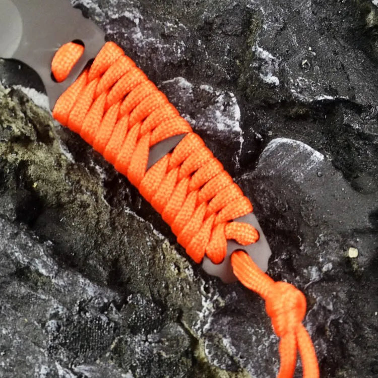 Straight camping survival knife with binding rope handle next to ABS sheath