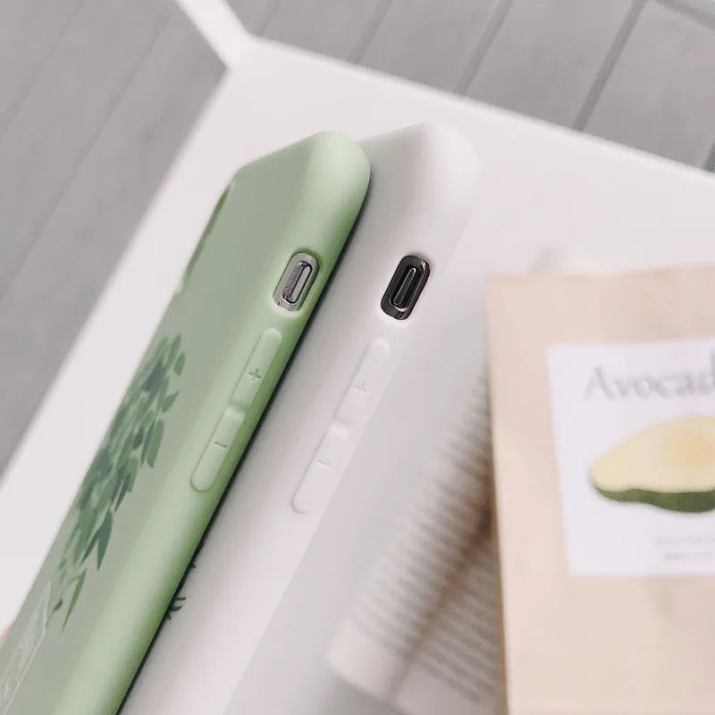 White silicone iPhone case with a detailed painted plant design on the back, showing the smooth texture and enclosed edges.