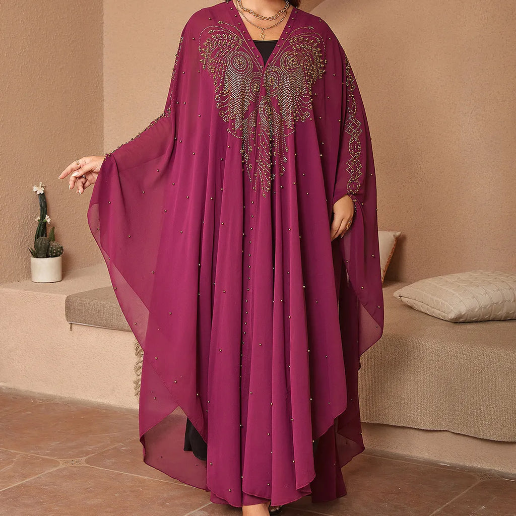 A woman wearing a long purple chiffon cape with rhinestone beading draped over the shoulders.