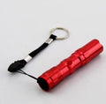 Black aluminium mini LED flashlight on a dark background.