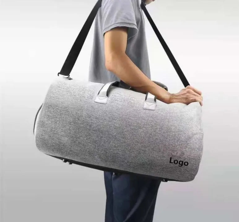 Travel garment bag in black and gray with adjustable shoulder strap, hanging suit carrier, and multiple pockets on a neutral background