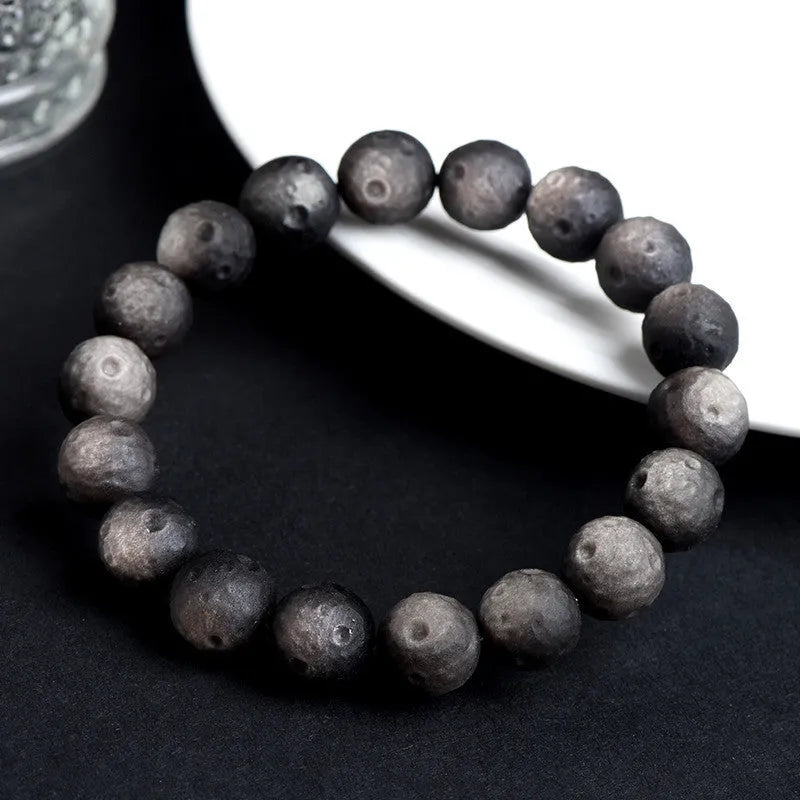 Natural obsidian crater ball bracelet in silver or gold finish, showing textured bead detail.
