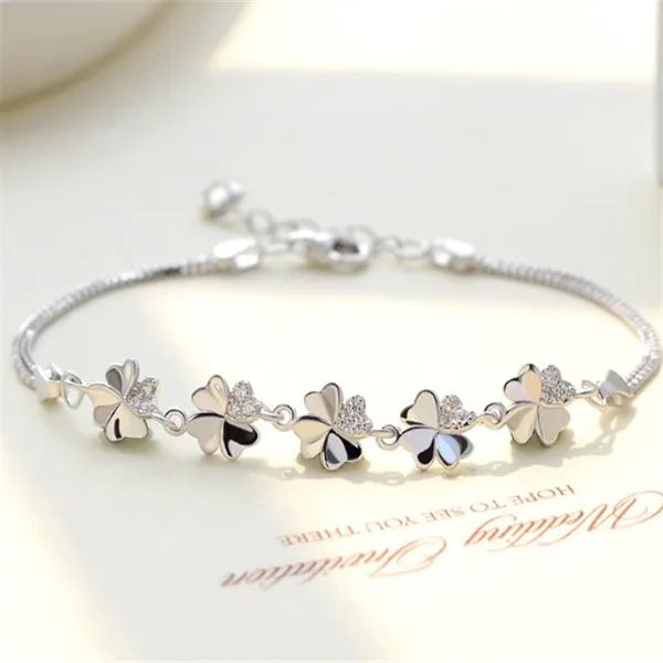 Silver four-leaf clover bracelet with adjustable chain on white background