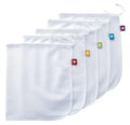 Five white cotton drawstring bags for kitchen vegetable storage arranged on a clean surface