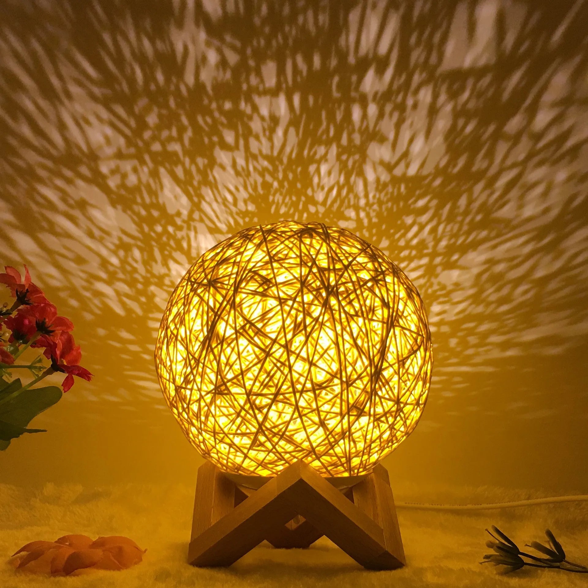 Rattan ball table lamp with woven shade and warm LED lighting on wooden surface