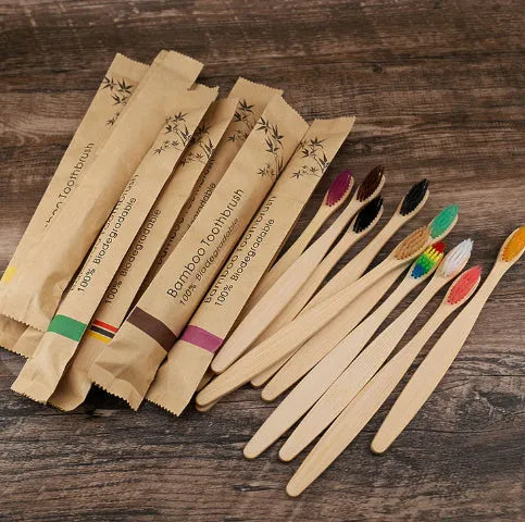 10 multi-coloured natural bamboo toothbrushes with soft charcoal bristles arranged on a white background