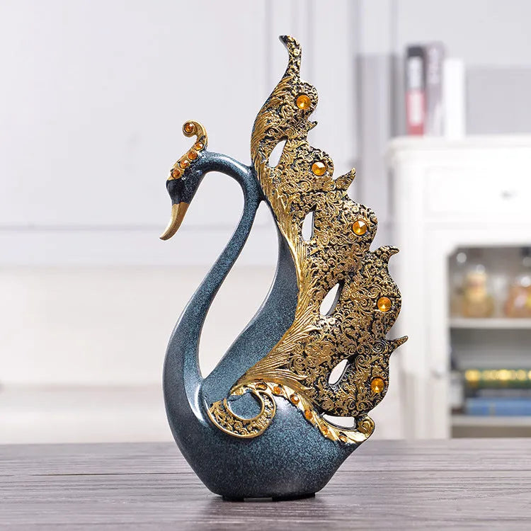 Resin couple swan figurines in blue and gold, large 29cm and small 24cm, on a wooden table