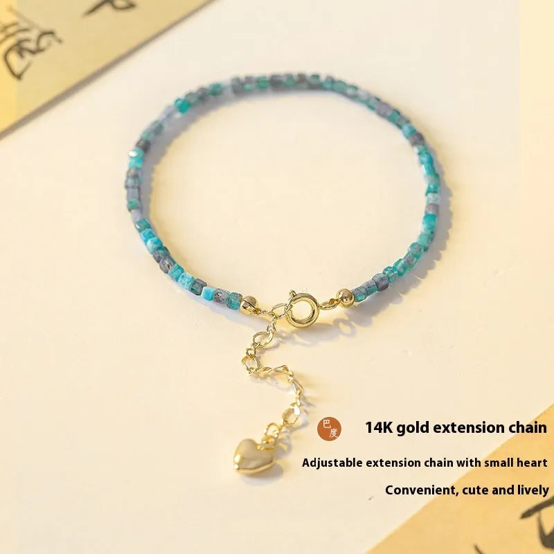Women's blue and grey apatite crystal bracelet with diamond-cut stones on a wrist.