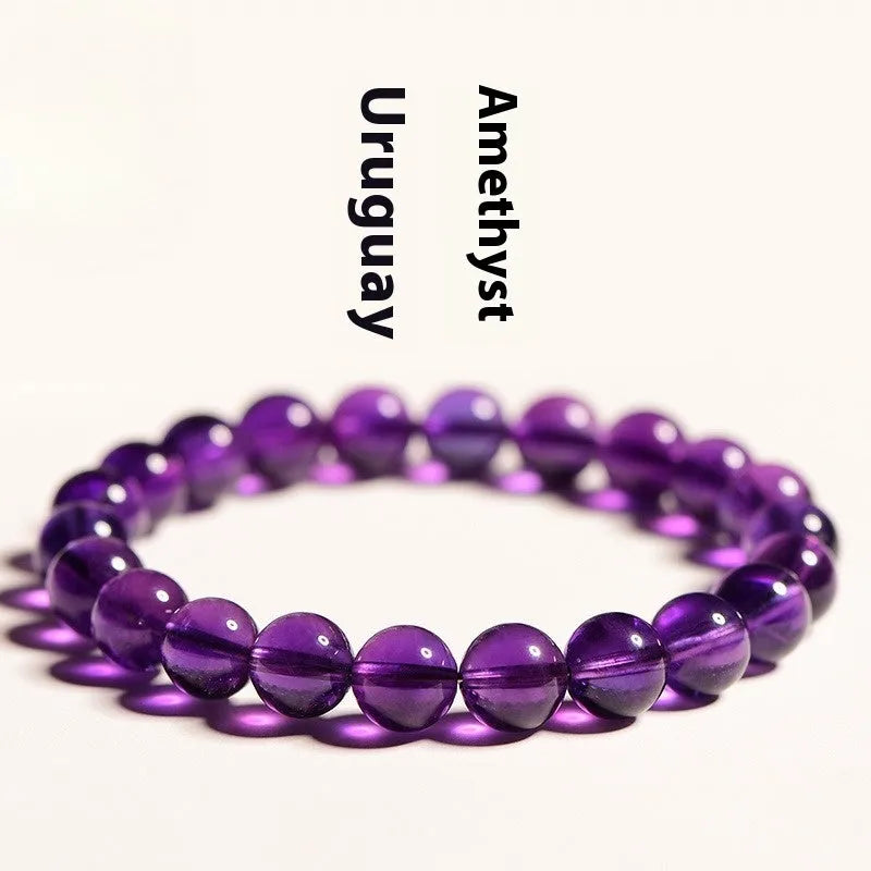 Close-up of a natural purple amethyst bead bracelet with elastic band on a wrist.