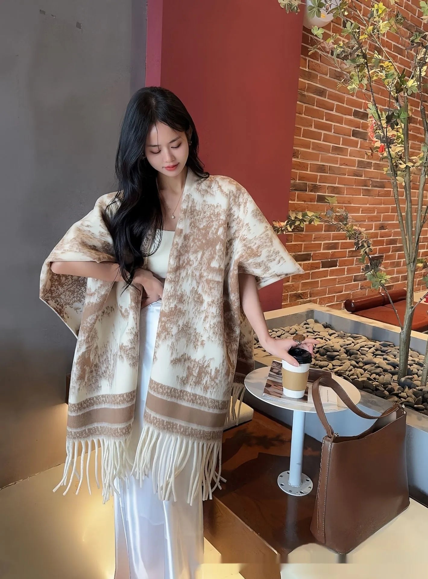Women's polyester scarf cape with tassel fringe in a printed floral design, worn as a shawl.