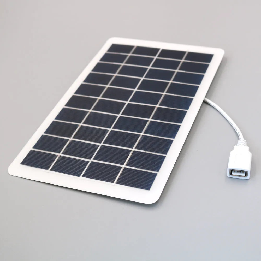Black portable solar panel charger with USB port for mobile phones on a textured surface.