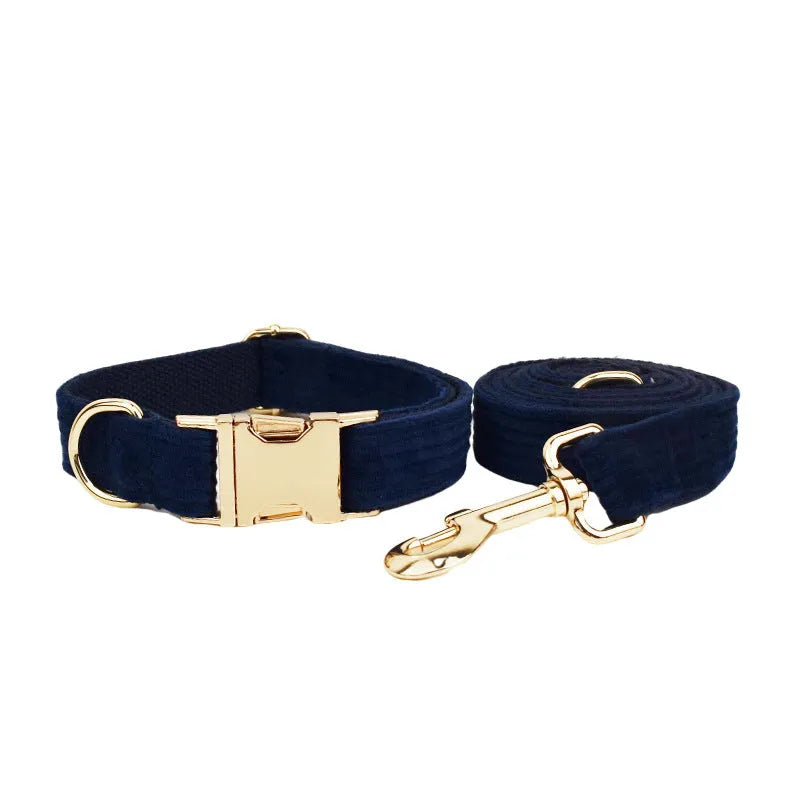 Navy blue corduroy dog collar and leash five-piece set with bow, vest, and poop bag on a wooden floor