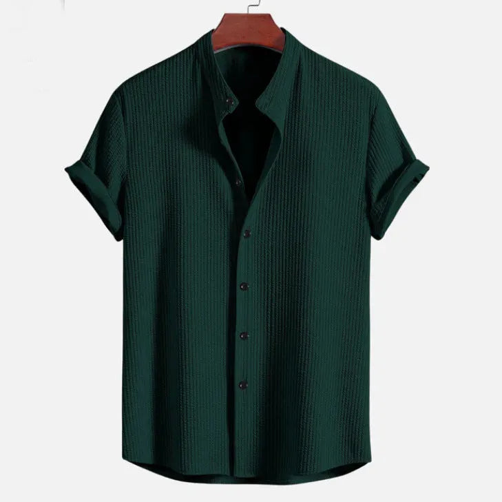 A man wearing a loose-fitting short sleeve casual shirt in a solid colour.