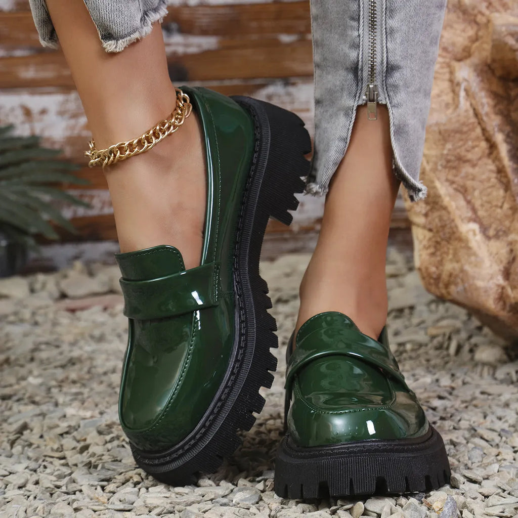 Women's black slip-on loafers with a chunky platform heel and rubber sole, shown from the side.