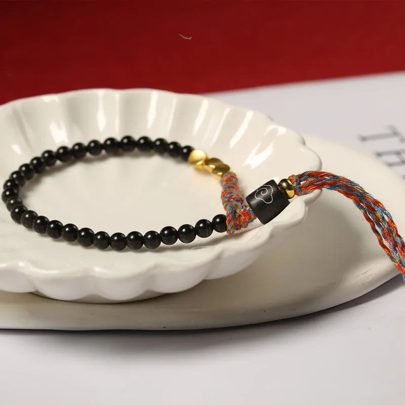 Hand-woven obsidian carrying strap bracelet showing textured surface and adjustable length