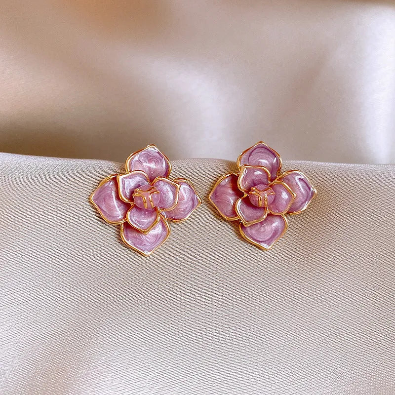 A pair of gold-plated purple oil-spot glaze flower stud earrings made from copper, showing detailed floral texture.