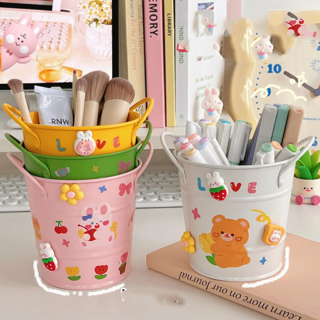 Round metal pen holder in a choice of colours, some with decorative sticker patches, on a wooden desk.