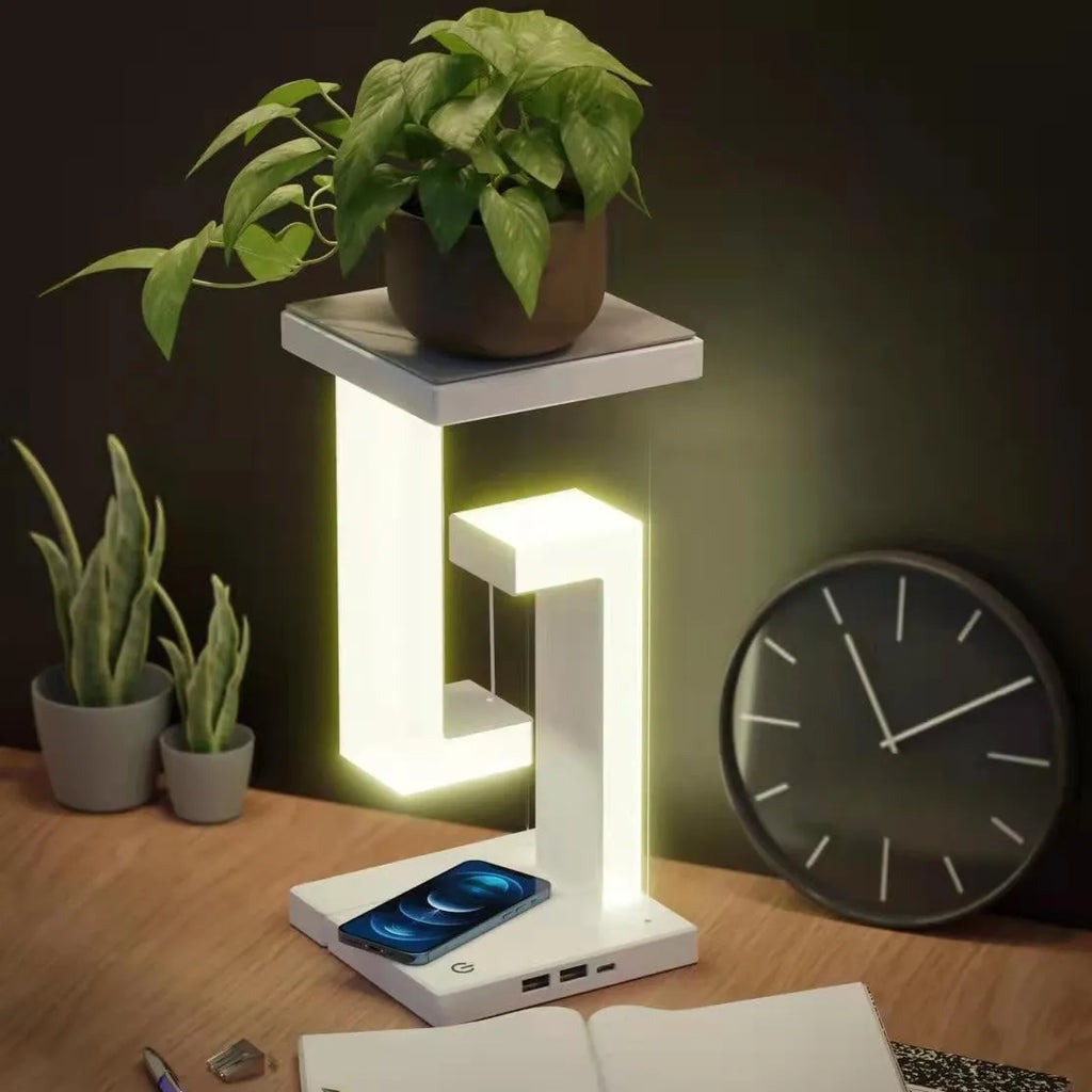 White magnetic suspension table lamp with wireless charging base, floating shade, and foldable bracket on a desk