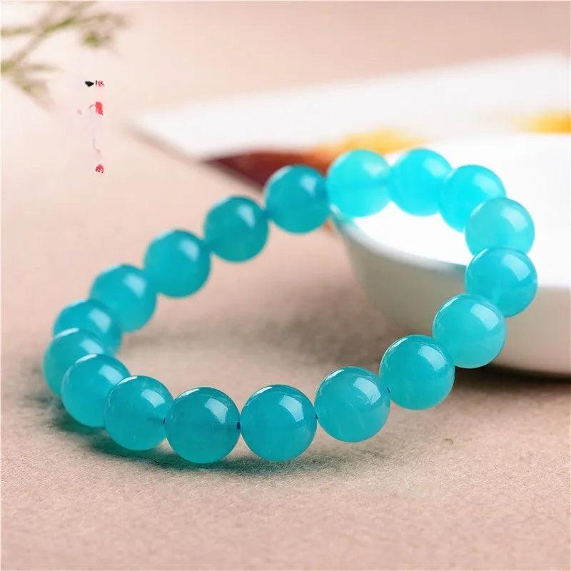 Selection of natural green Amazonite scattered beads in different sizes on a white background.