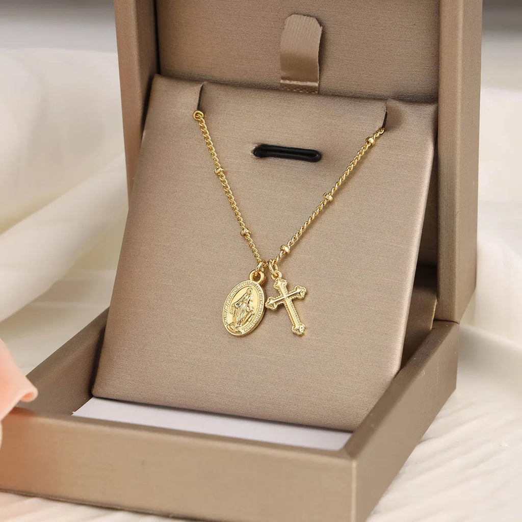 Geometric gold cross Virgin Mary pendant necklace with a simple design on a chain.