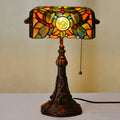 Tiffany-style table lamp with colourful stained glass shade and resin base on a desk