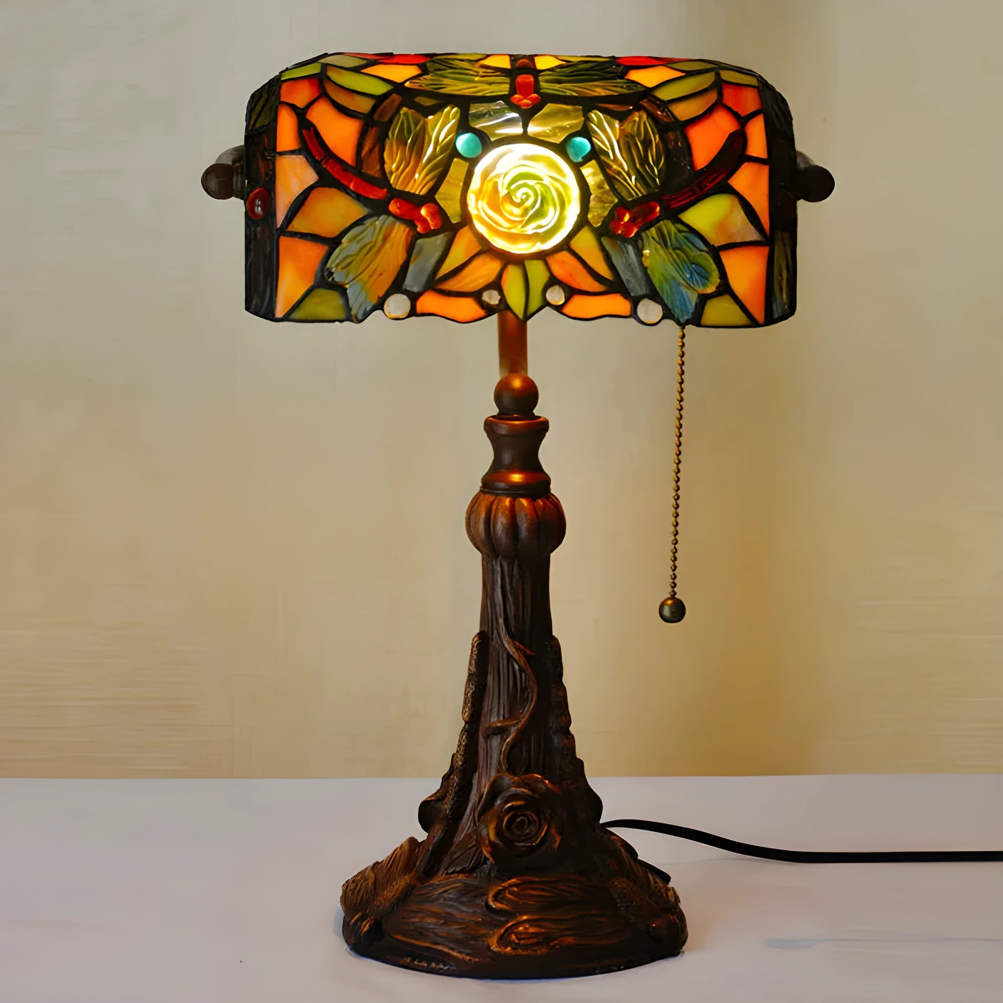Tiffany-style table lamp with colourful stained glass shade and resin base on a desk
