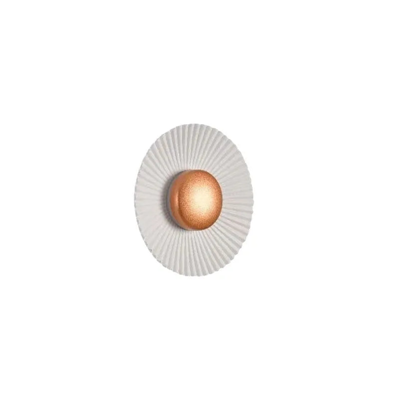 Round aluminium wall lamp in an outer white and inner gold colour combination, mounted on a wall.