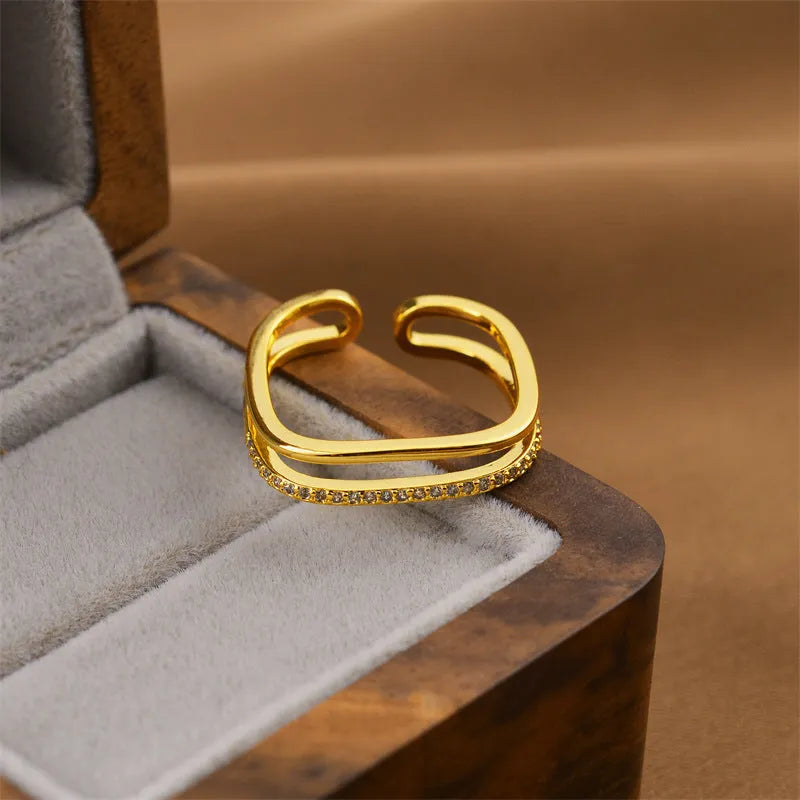 Gold open geometric women's fashion ring on a plain background.