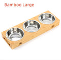Solid wood elevated pet feeder with stainless steel bowls in a bamboo finish on a wooden floor.
