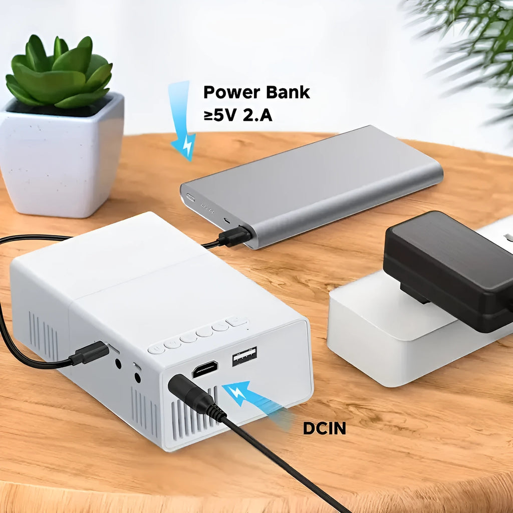 Black and white M100 mini portable LED home projector with remote control on a table.