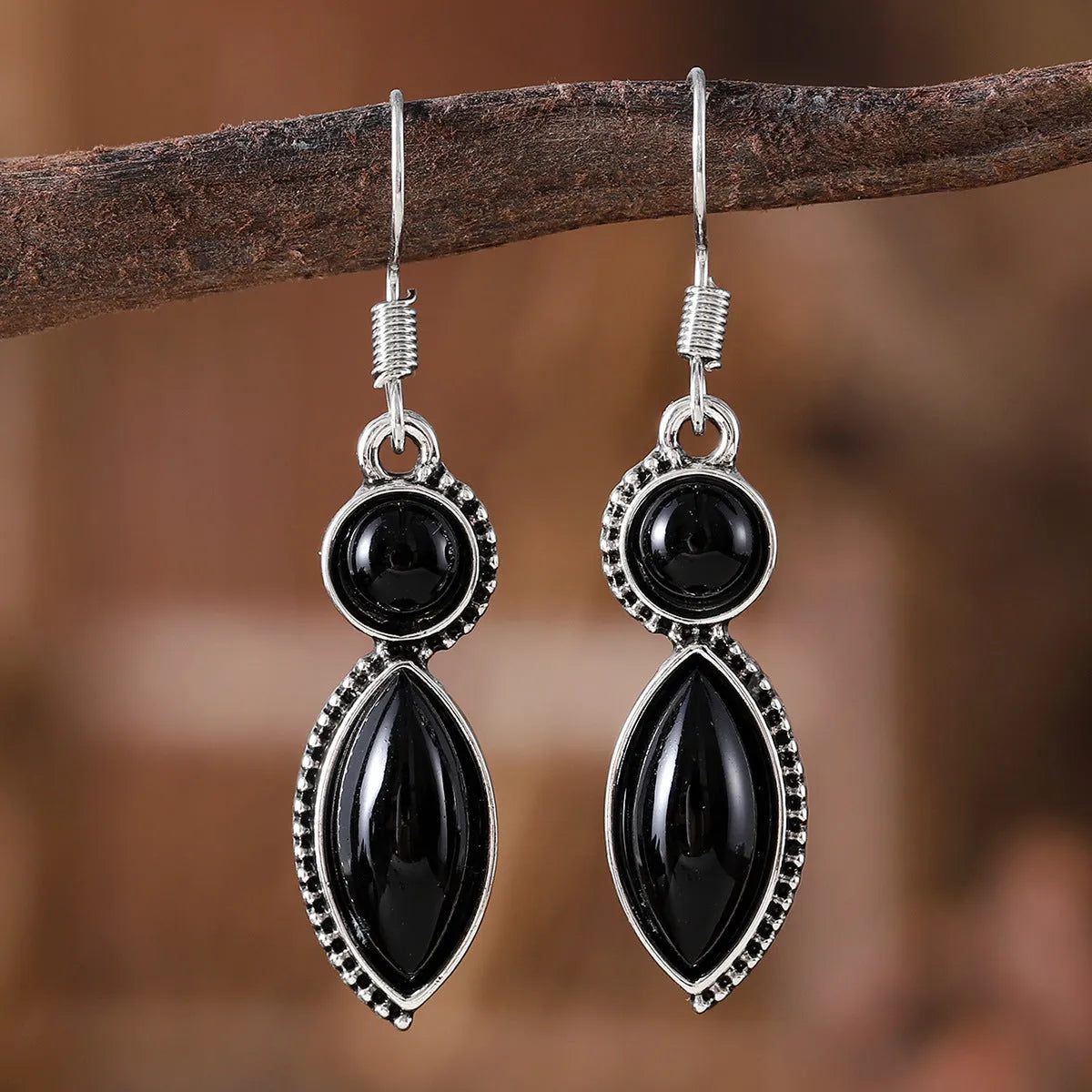 Close-up of geometric vintage pendant earrings in black and purple with a metallic shine.