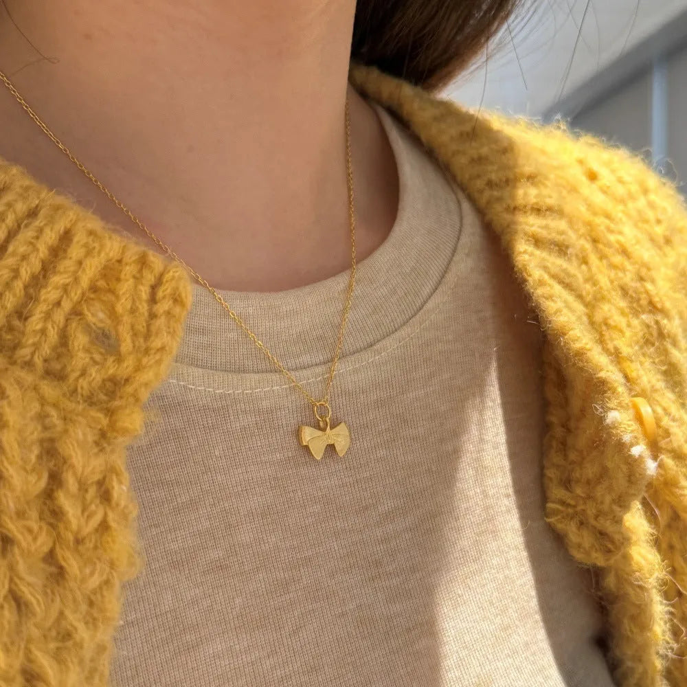 Matte bow pendant necklace in 925 silver with platinum electroplated finish on display
