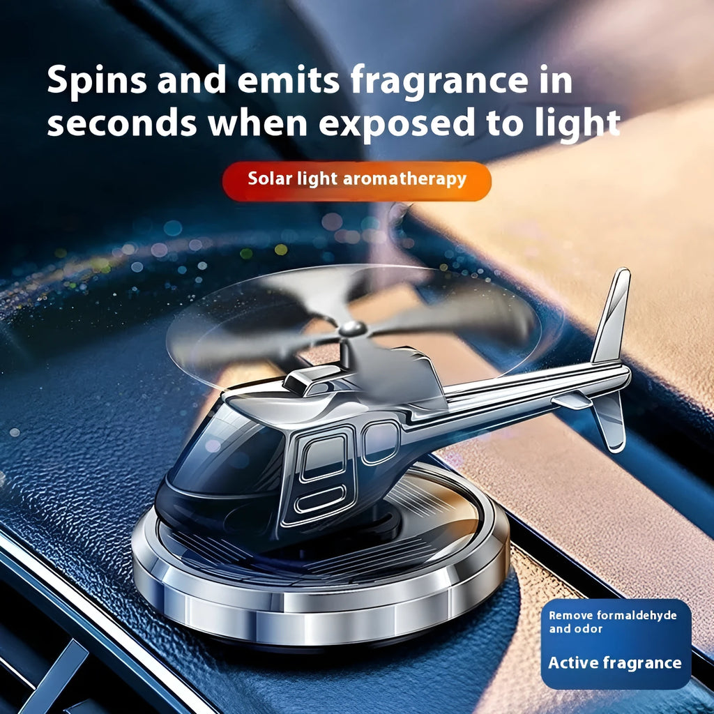 Silver metal solar-powered helicopter car air freshener with rotating blades on a dashboard