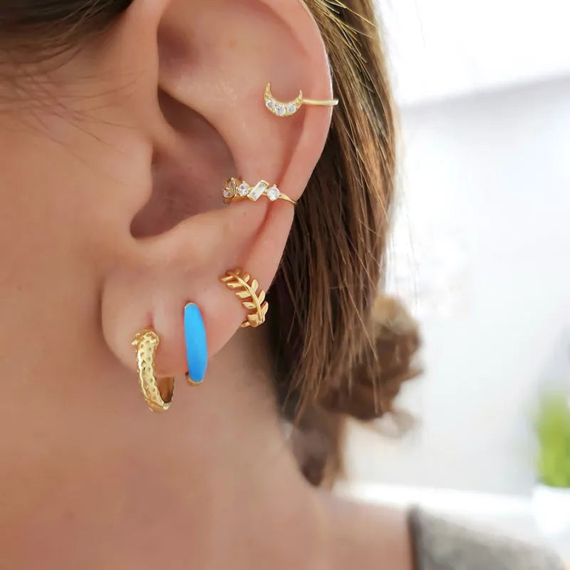 A pair of curved U-shaped drop earrings with a glossy light green oval and ring geometric design on copper wire.