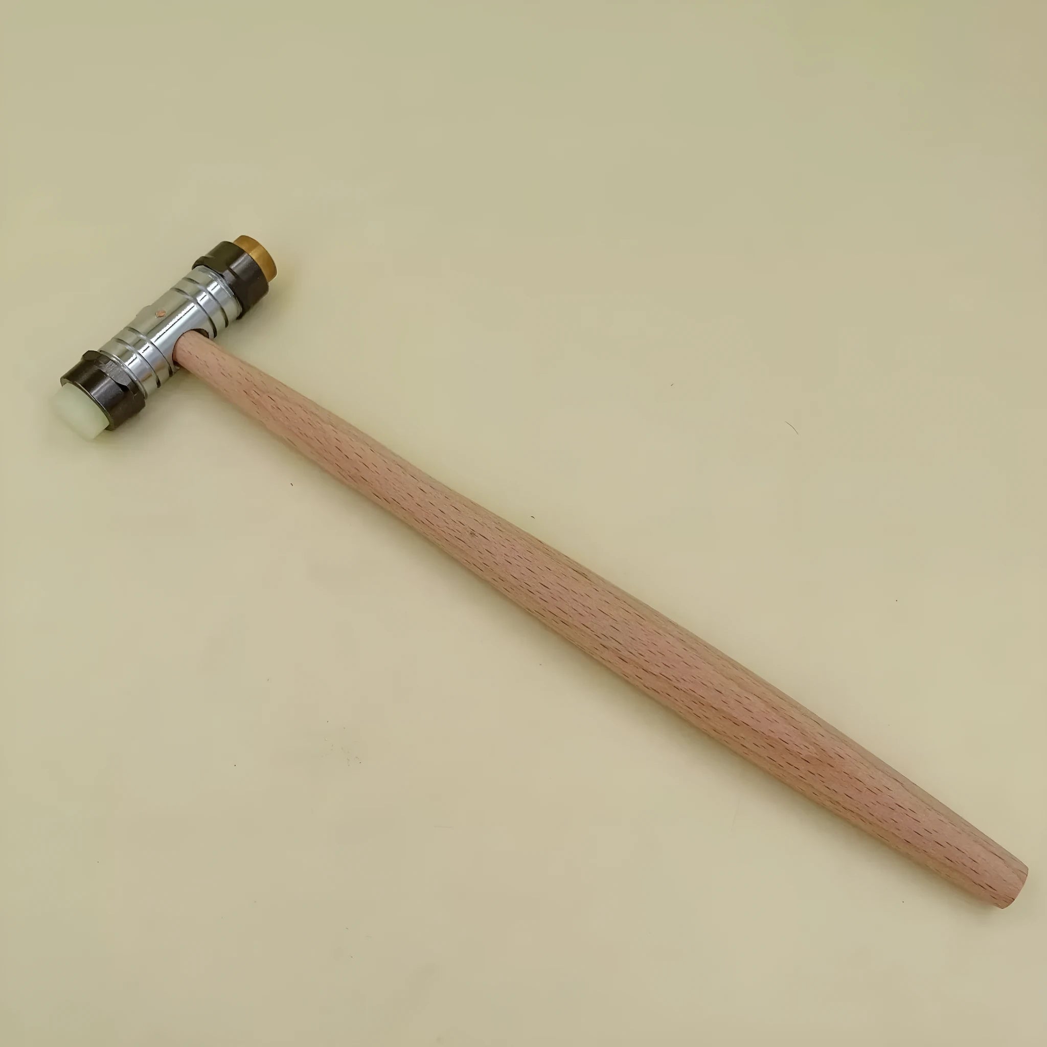 Brass watch repair hammer with wooden handle on a workbench