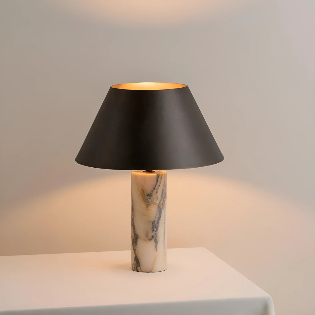 Modern black table lamp with a textured marble base on a wooden desk.