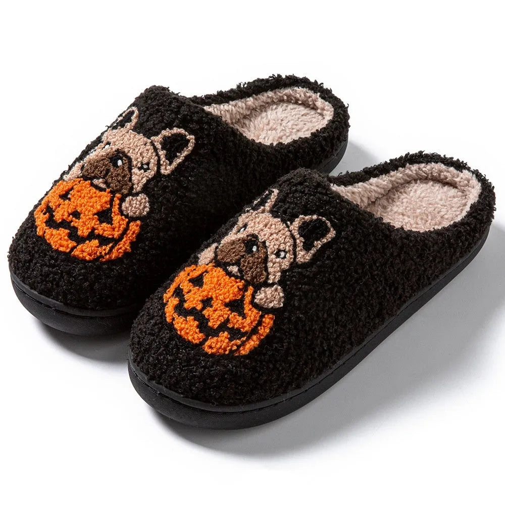 Pair of black plush house slippers with orange pumpkin print and a textured non-slip rubber sole.