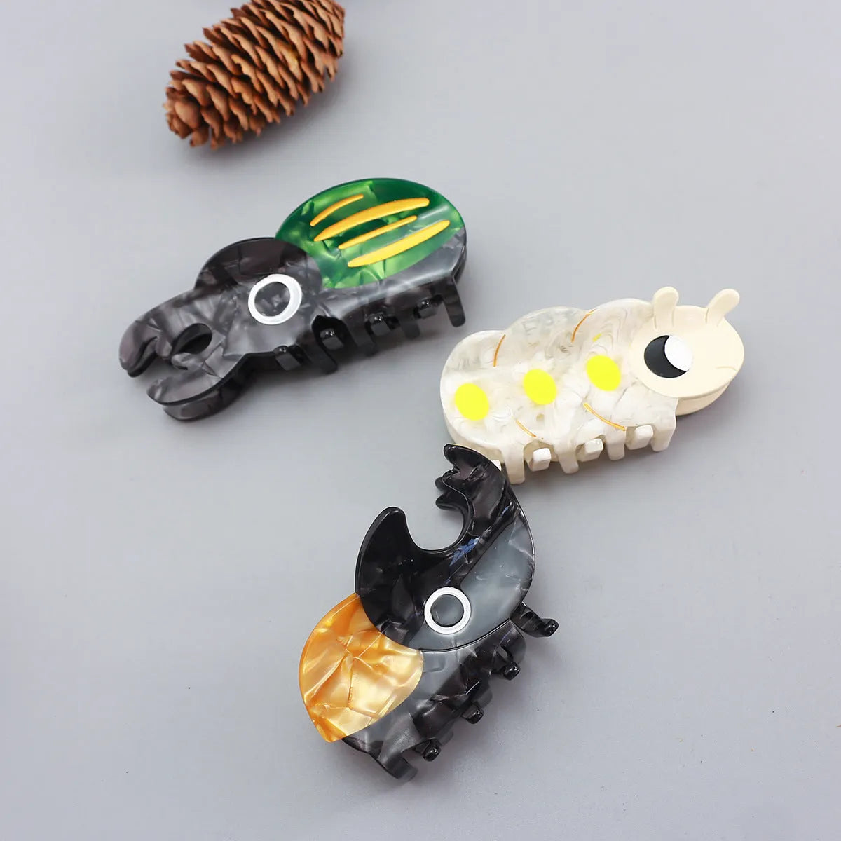 Handmade cellulose acetate beetle grip accessory with cartoon insect biology design in green or orange colour