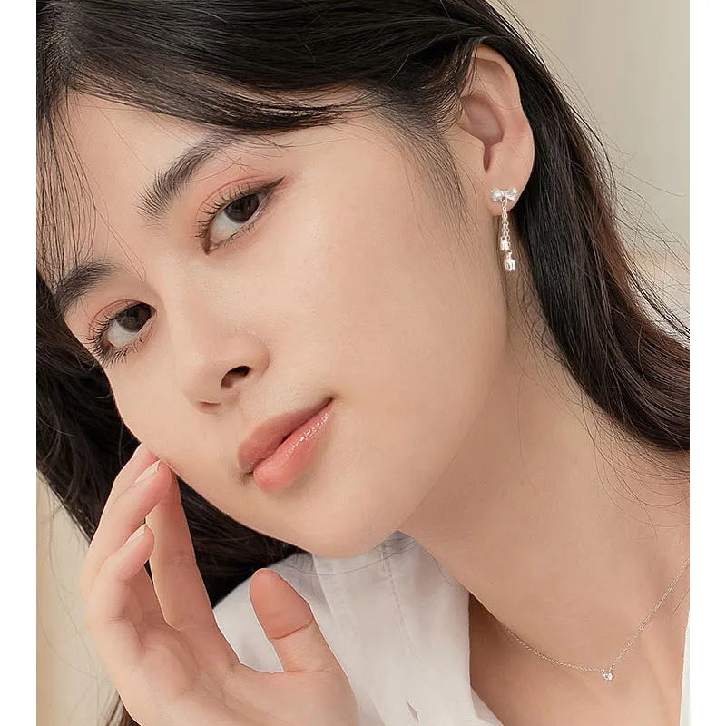 Silver bow ear studs with sweet tassel details and Korean style design for women