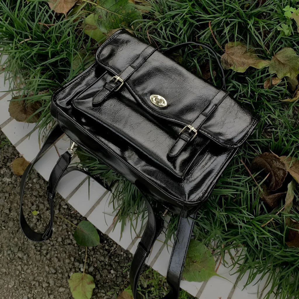 Black college style messenger bag with oil wax leather finish showing shoulder strap and main compartment