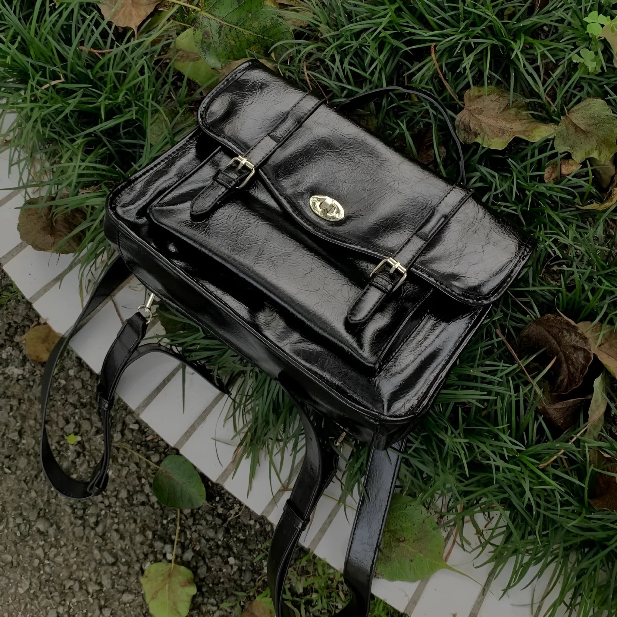 Black college style messenger bag with oil wax leather finish showing shoulder strap and main compartment