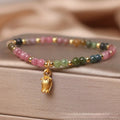 Natural tourmaline bead anklet for women with a silver flower charm on an ankle.