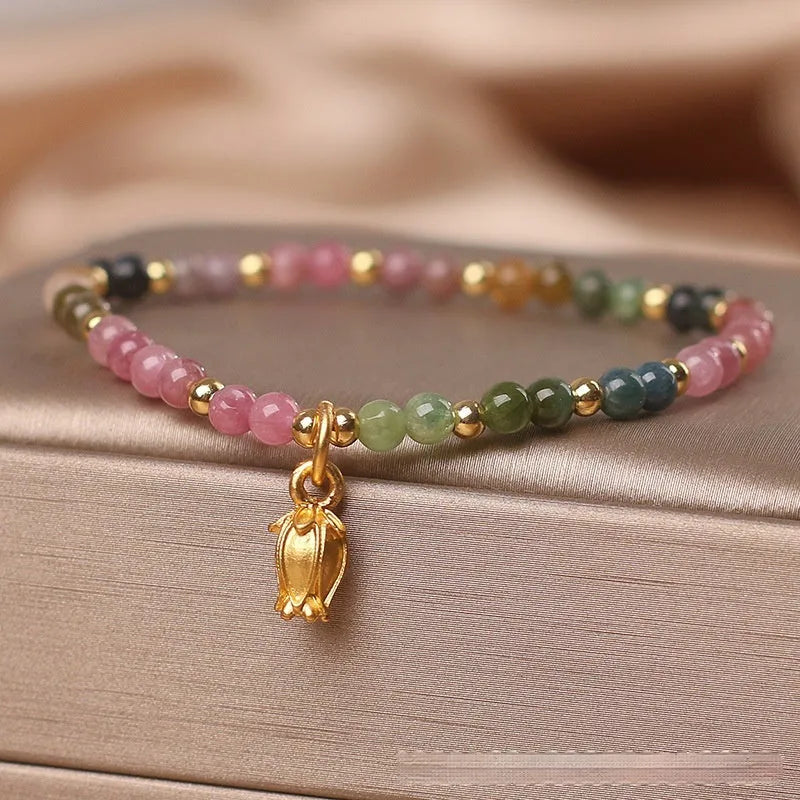 Natural tourmaline bead anklet for women with a silver flower charm on an ankle.