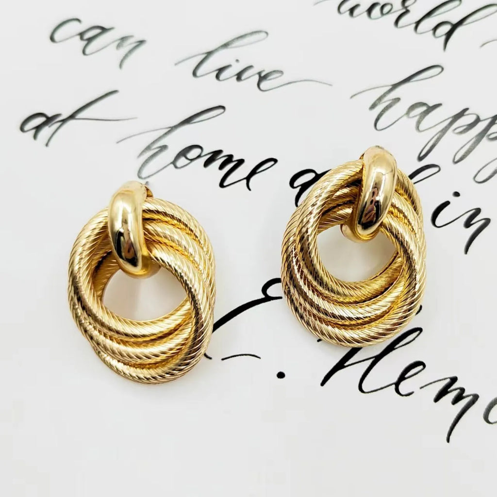 Gold geometric ring embossed twisted stud earrings on white background