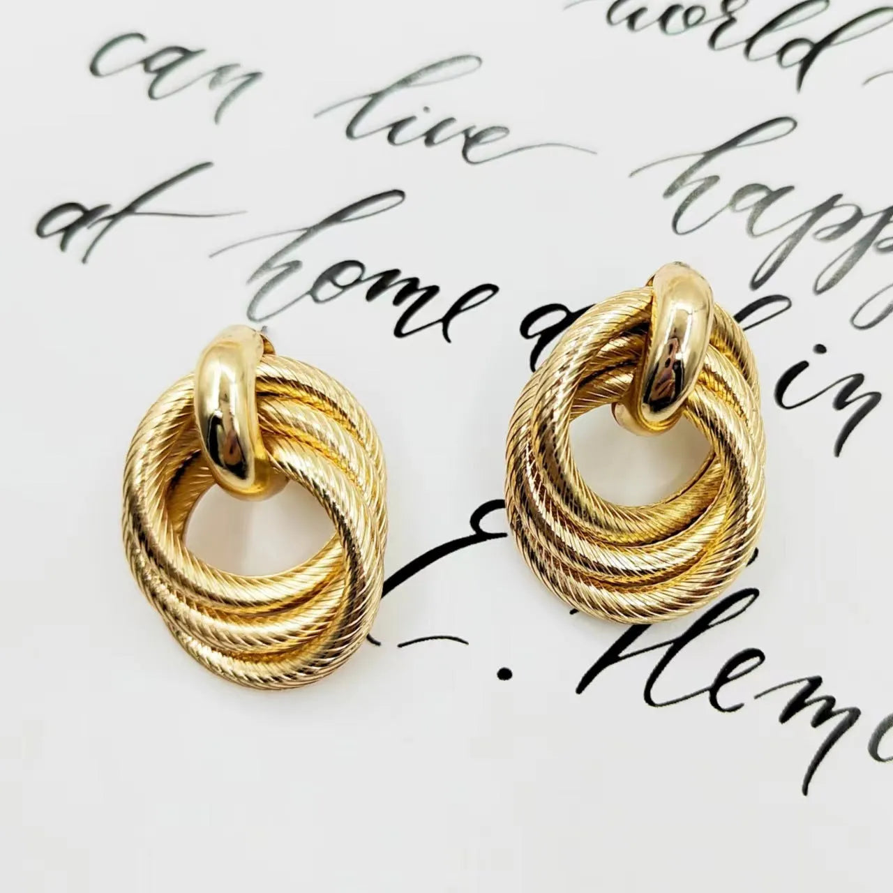 Gold geometric ring embossed twisted stud earrings on white background