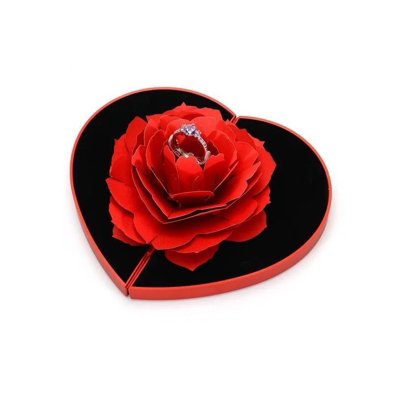 Red rotating 3D heart-shaped plastic ring box with a rose, open to show ring placement.